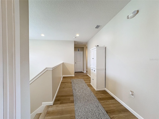 hallway with hardwood / wood-style floors and a textured ceiling