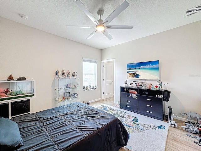 bedroom featuring ceiling fan, hardwood / wood-style floors, and a textured ceiling