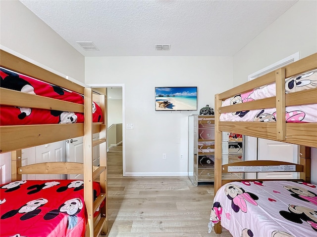 bedroom featuring light hardwood / wood-style floors and a textured ceiling