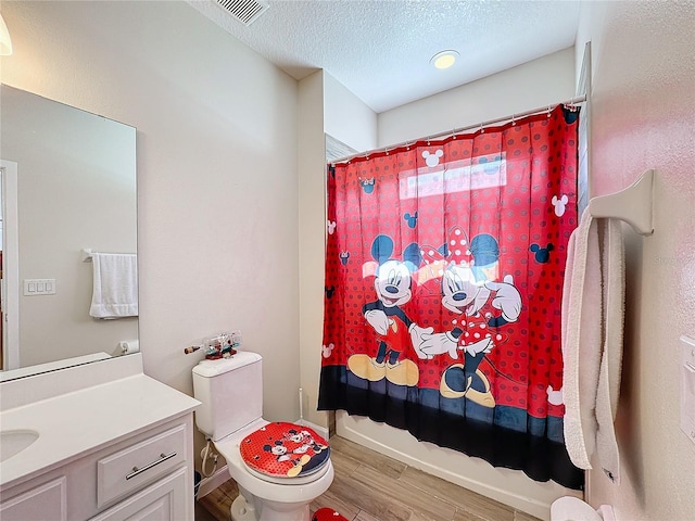 full bathroom with shower / bathtub combination with curtain, hardwood / wood-style floors, a textured ceiling, toilet, and vanity