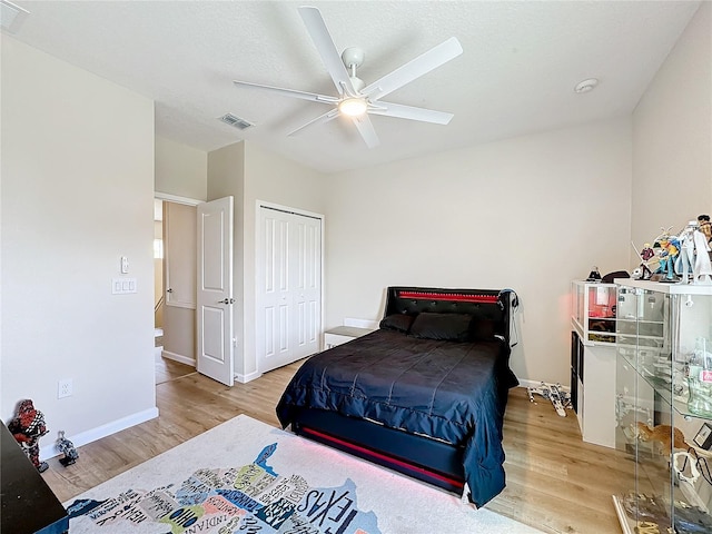 bedroom with a closet, light hardwood / wood-style floors, and ceiling fan