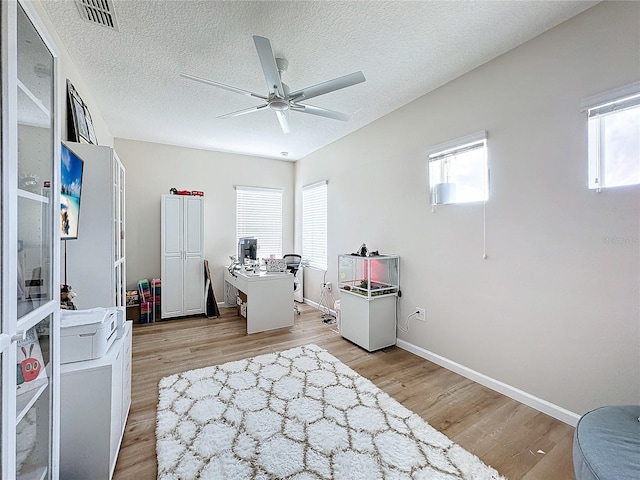 interior space with plenty of natural light, ceiling fan, light wood-type flooring, and a textured ceiling