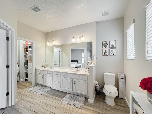 bathroom featuring hardwood / wood-style flooring, vanity, toilet, and a textured ceiling