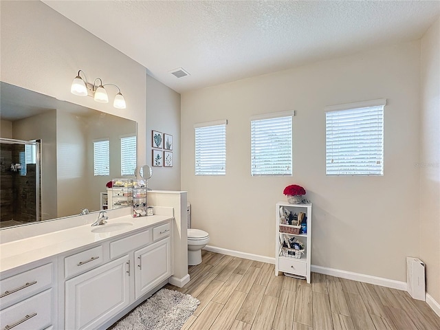 bathroom with vanity, a textured ceiling, hardwood / wood-style flooring, and toilet