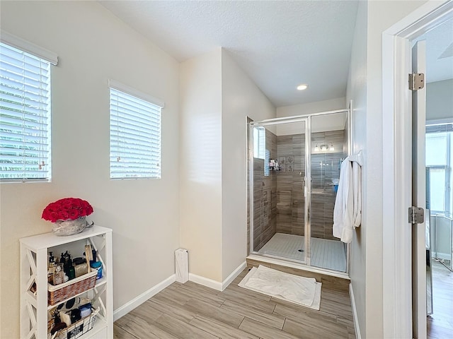 bathroom featuring hardwood / wood-style floors, a shower with shower door, and a wealth of natural light