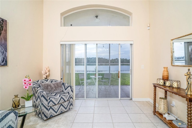 interior space with a water view, light tile patterned floors, and a towering ceiling