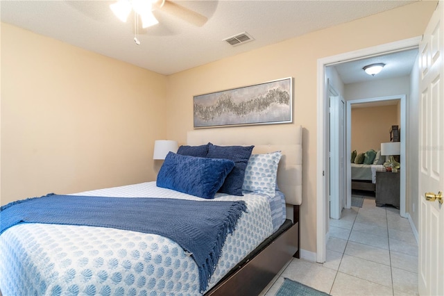 bedroom featuring ceiling fan, light tile patterned flooring, and a textured ceiling