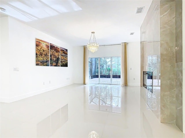 empty room with tile patterned flooring, a notable chandelier, and a wealth of natural light