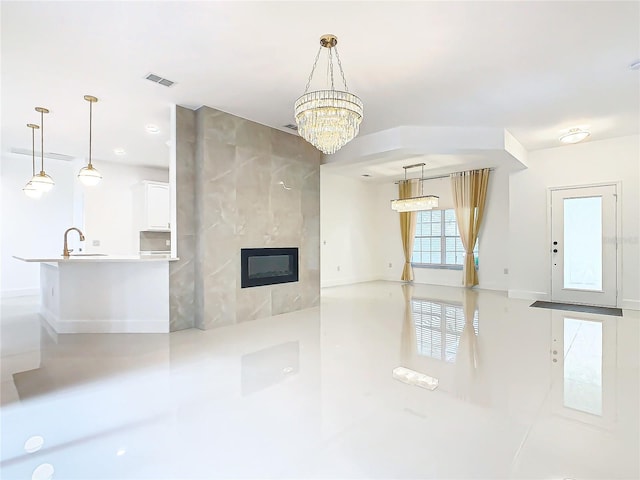 unfurnished living room featuring a tile fireplace, sink, and a chandelier