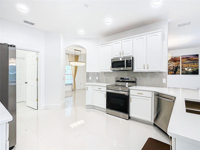 kitchen with white cabinets, decorative light fixtures, stainless steel appliances, and tasteful backsplash