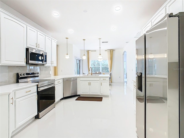 kitchen featuring kitchen peninsula, appliances with stainless steel finishes, sink, pendant lighting, and white cabinetry