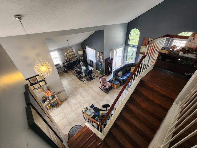 living room with high vaulted ceiling, a notable chandelier, a healthy amount of sunlight, and wood-type flooring