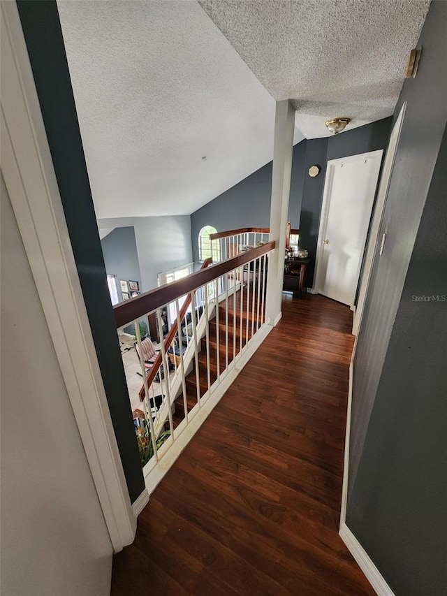 hallway featuring dark hardwood / wood-style flooring, lofted ceiling, and a textured ceiling