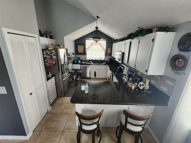 kitchen featuring white cabinetry, stainless steel appliances, pendant lighting, and vaulted ceiling