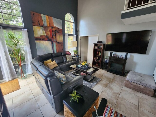 tiled living room with a fireplace and a high ceiling