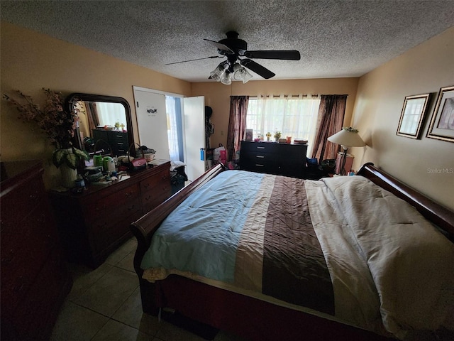 bedroom with a textured ceiling, light tile patterned floors, and ceiling fan