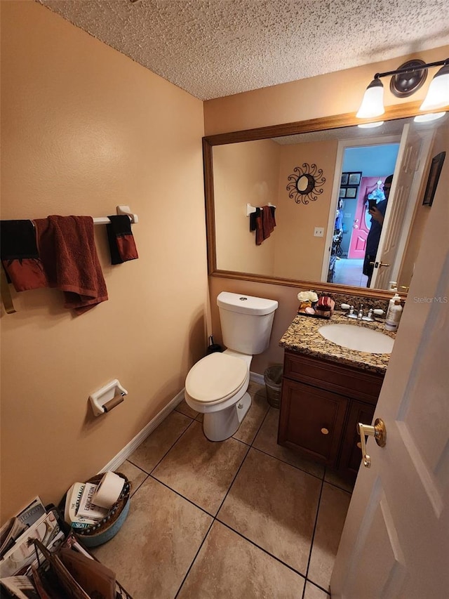 bathroom featuring vanity, tile patterned floors, toilet, and a textured ceiling