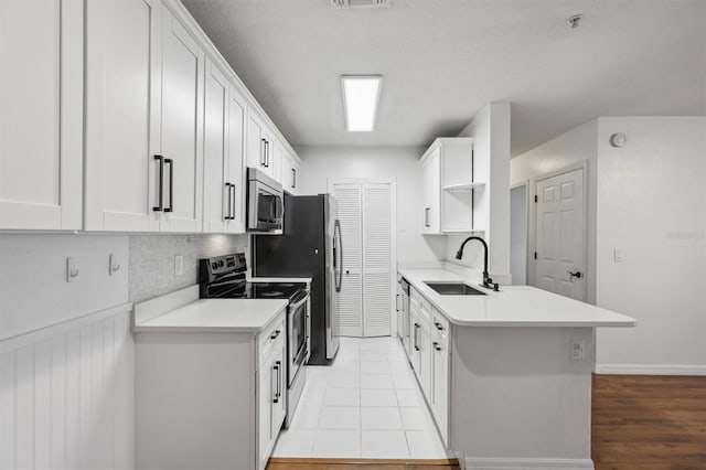 kitchen featuring sink, tasteful backsplash, light hardwood / wood-style flooring, white cabinets, and appliances with stainless steel finishes