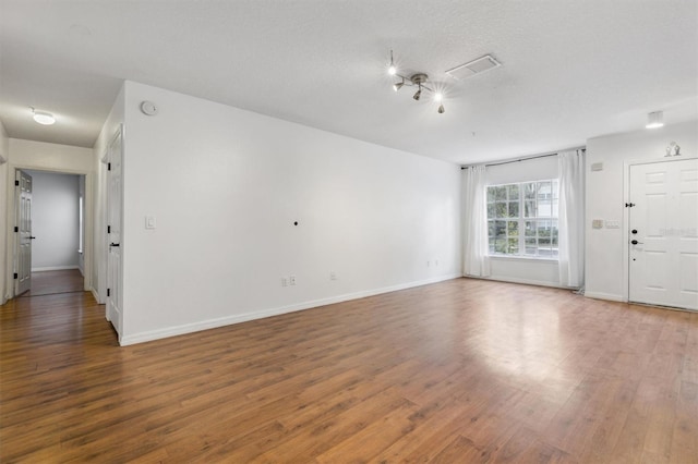 spare room featuring dark hardwood / wood-style flooring and a textured ceiling