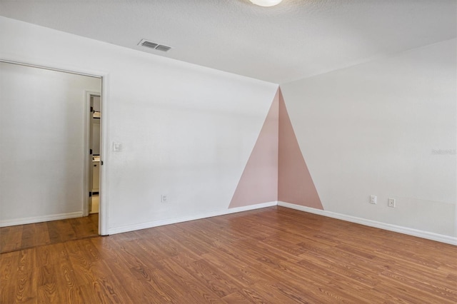 empty room with a textured ceiling and hardwood / wood-style flooring