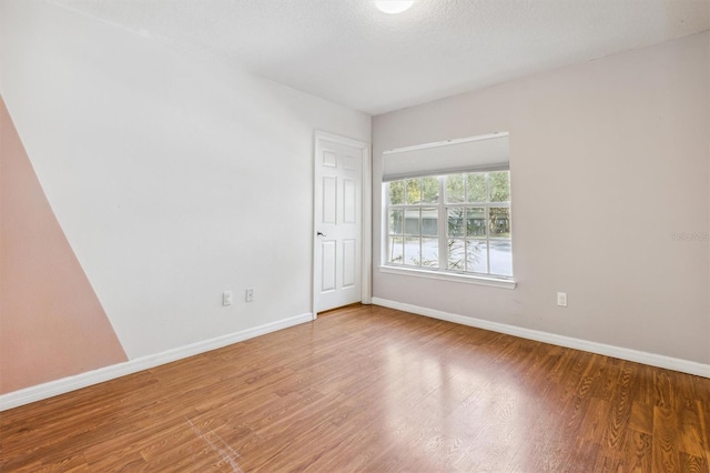 empty room featuring wood-type flooring and a textured ceiling