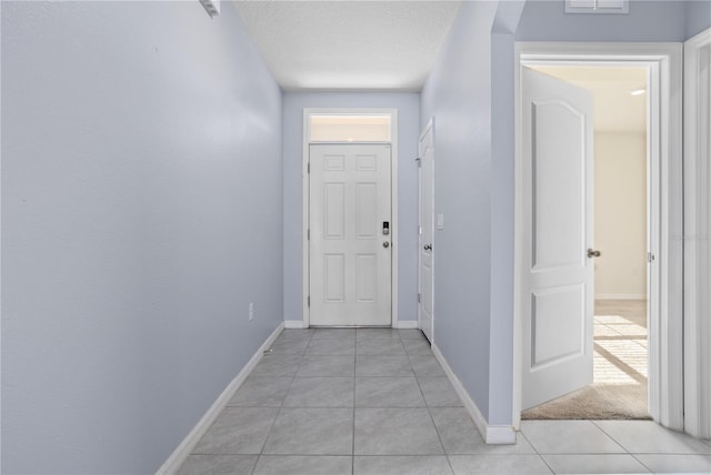 hall with light tile patterned flooring and a textured ceiling