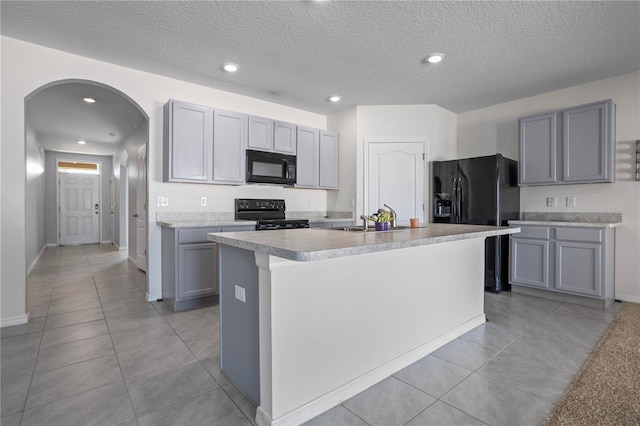 kitchen featuring black appliances, sink, an island with sink, and a textured ceiling