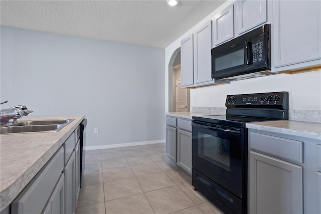 kitchen featuring sink, a textured ceiling, gray cabinets, light tile patterned flooring, and black appliances