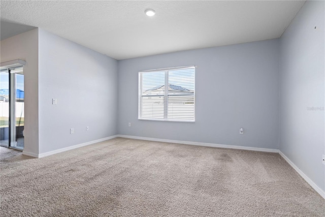 unfurnished room featuring a textured ceiling and light carpet