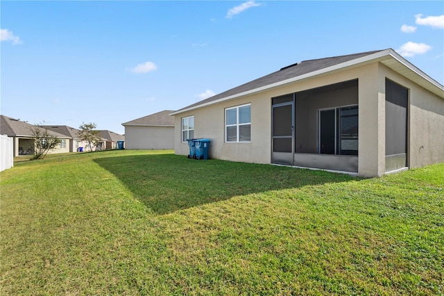 rear view of house featuring a sunroom and a yard