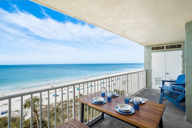 balcony with a water view and a view of the beach