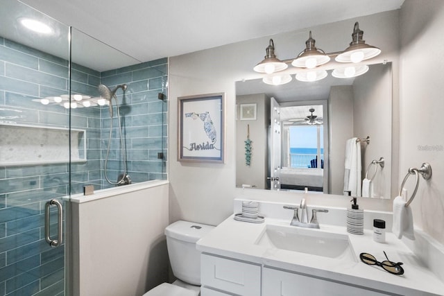 bathroom with vanity, ceiling fan, toilet, and a shower with door