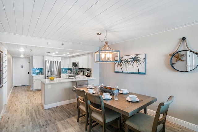 dining area with a chandelier, sink, wooden ceiling, and light hardwood / wood-style floors