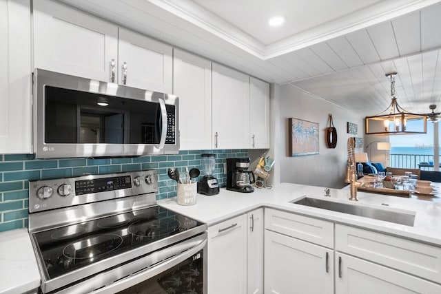 kitchen featuring white cabinets, stainless steel appliances, a chandelier, and sink