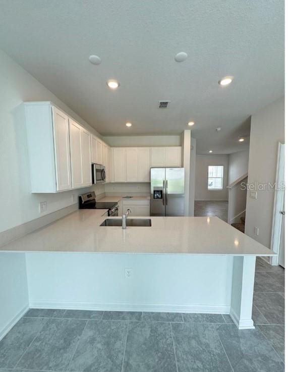 kitchen featuring kitchen peninsula, white cabinetry, sink, and appliances with stainless steel finishes