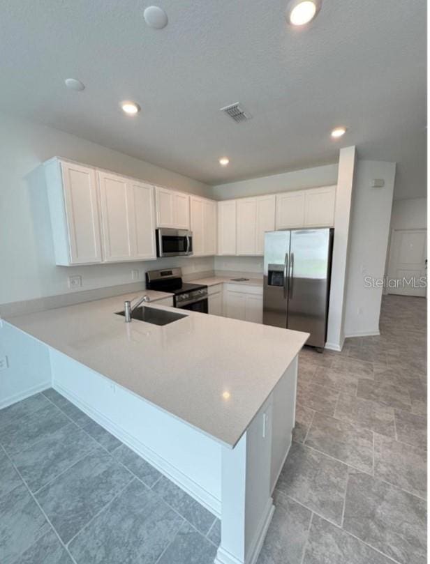 kitchen featuring white cabinetry, kitchen peninsula, sink, and stainless steel appliances