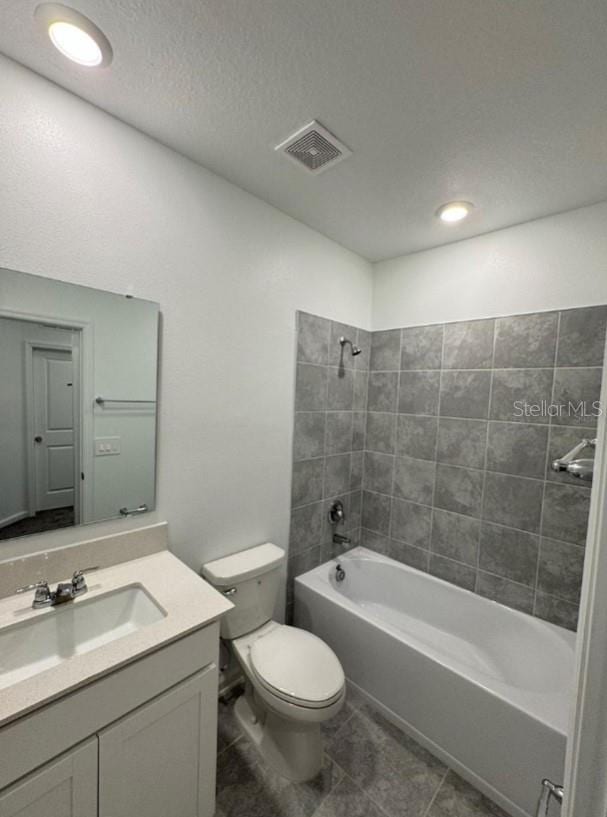 full bathroom with toilet, tile patterned flooring, a textured ceiling, tiled shower / bath combo, and vanity