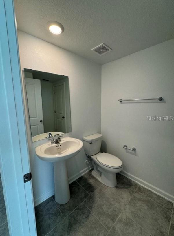 bathroom featuring tile patterned floors, a textured ceiling, and toilet