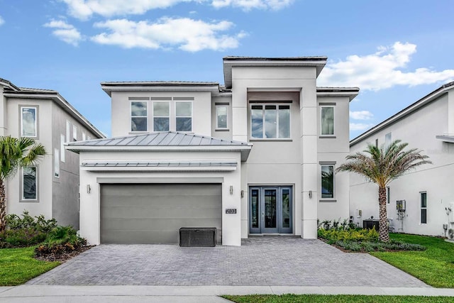 view of front of home featuring french doors, central AC, and a garage