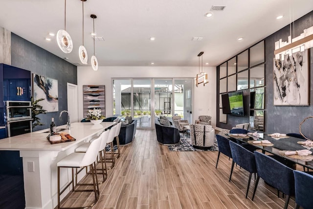 kitchen with a wealth of natural light, light hardwood / wood-style floors, and decorative light fixtures