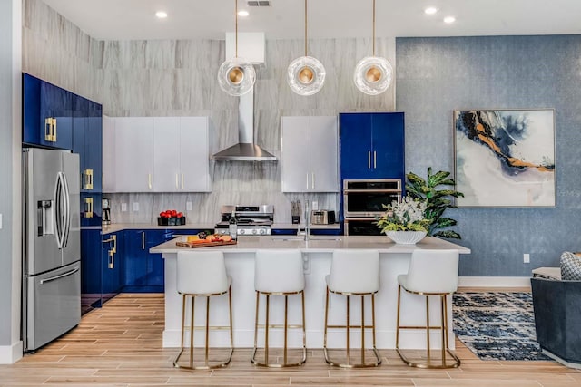 kitchen with pendant lighting, a kitchen breakfast bar, light wood-type flooring, white cabinetry, and stainless steel appliances