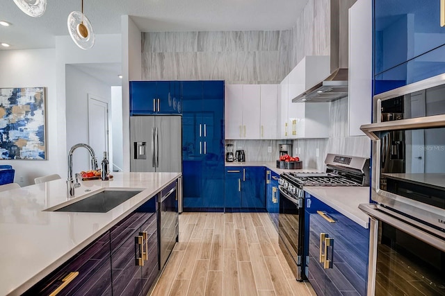 kitchen with blue cabinetry, white cabinetry, sink, hanging light fixtures, and appliances with stainless steel finishes