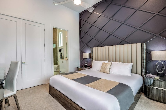 carpeted bedroom featuring ceiling fan, ensuite bath, and a closet