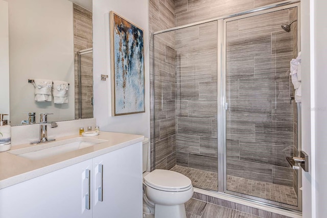 bathroom featuring vanity, toilet, and a shower with door