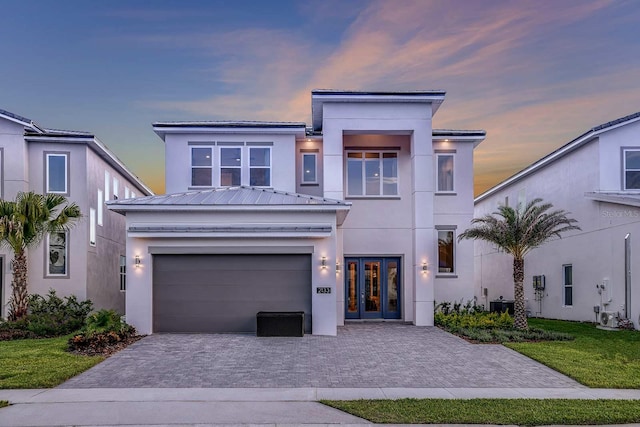 modern home with a yard, french doors, cooling unit, and a garage