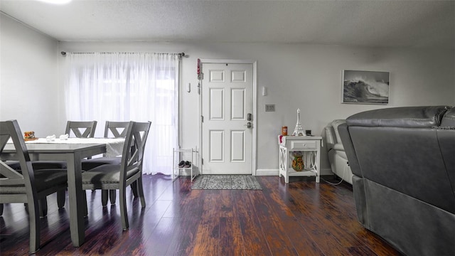 dining area featuring dark wood-type flooring and a textured ceiling