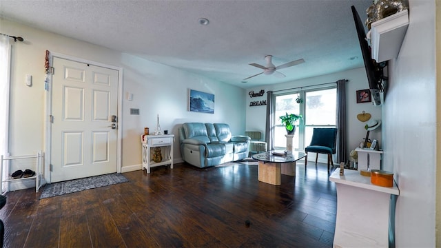 living room featuring dark hardwood / wood-style flooring, a textured ceiling, and ceiling fan