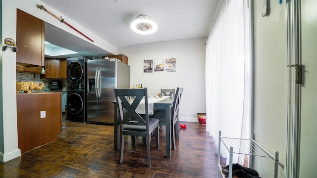 dining space with dark wood-type flooring, stacked washing maching and dryer, and a textured ceiling