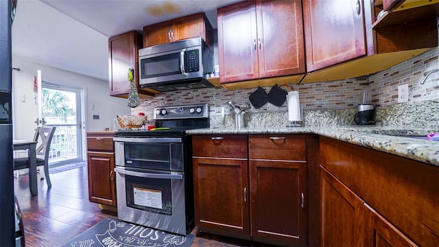 kitchen featuring dark hardwood / wood-style flooring, light stone countertops, appliances with stainless steel finishes, and backsplash