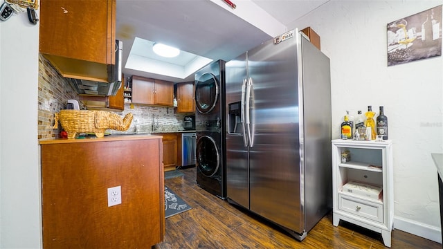 kitchen with dark hardwood / wood-style flooring, decorative backsplash, stainless steel fridge with ice dispenser, and stacked washer / dryer